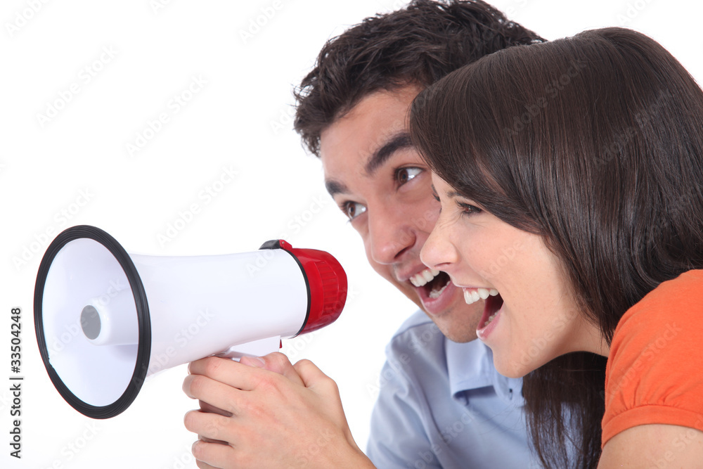 © auremar - Young couple shouting into a megaphone