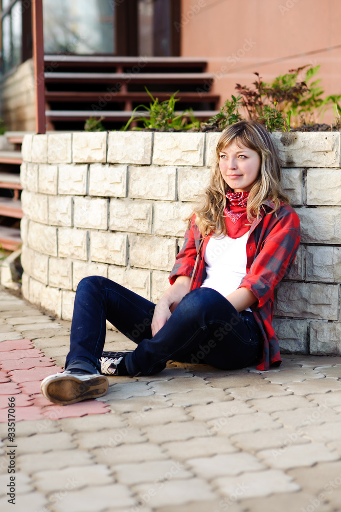 teenager in red skirt sitting on sidewalk