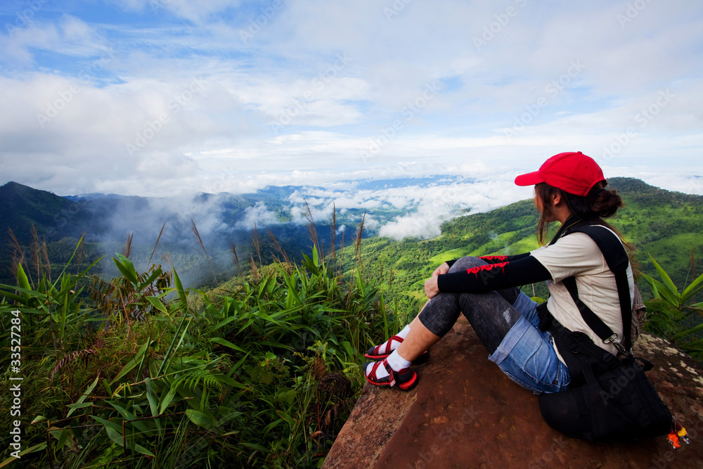 Young woman sitting on top of a mountain