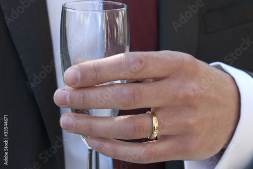 Hand holding glass with gold wedding ring photo