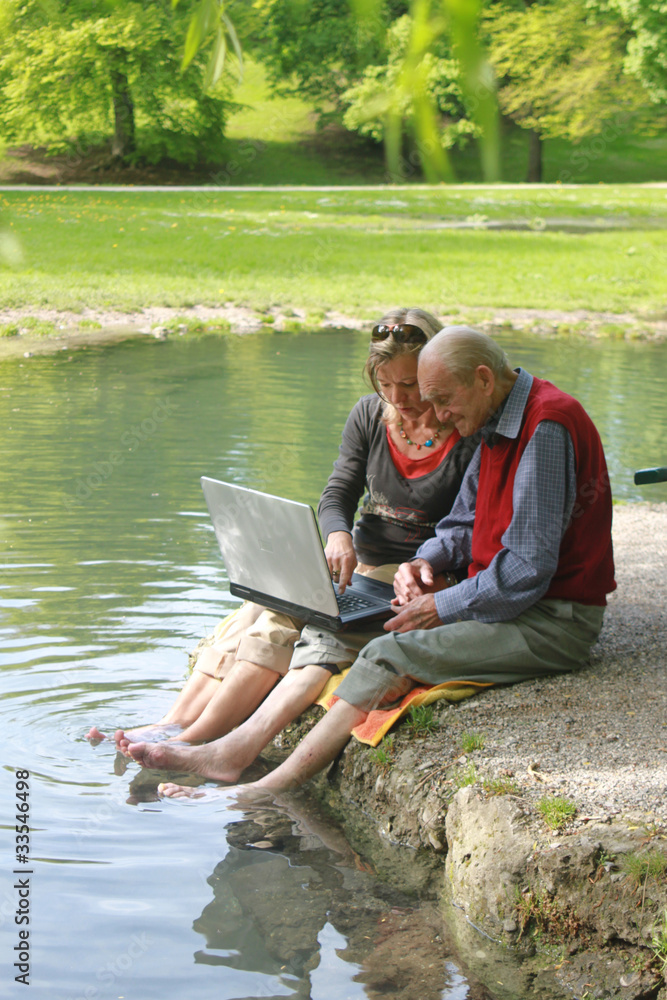 Alter Mann und junge Frau arbeiten am Laptop im Grünen