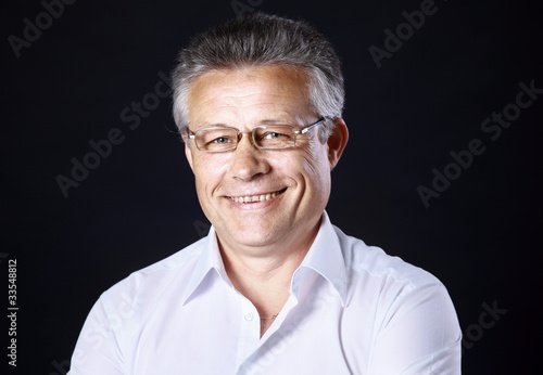 Portrait of successful business man standing on black