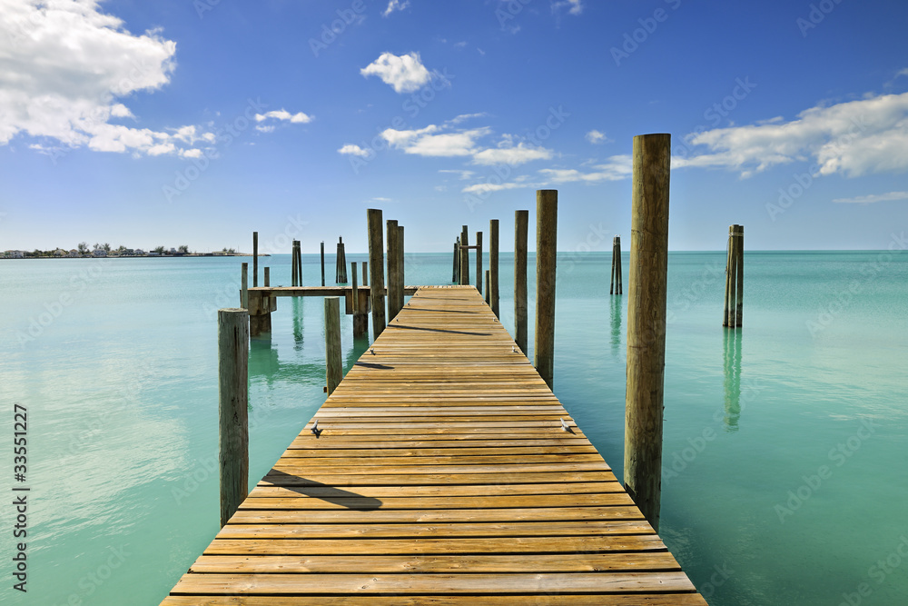 Mooring posts and pontoon leading in turquoise blue sea