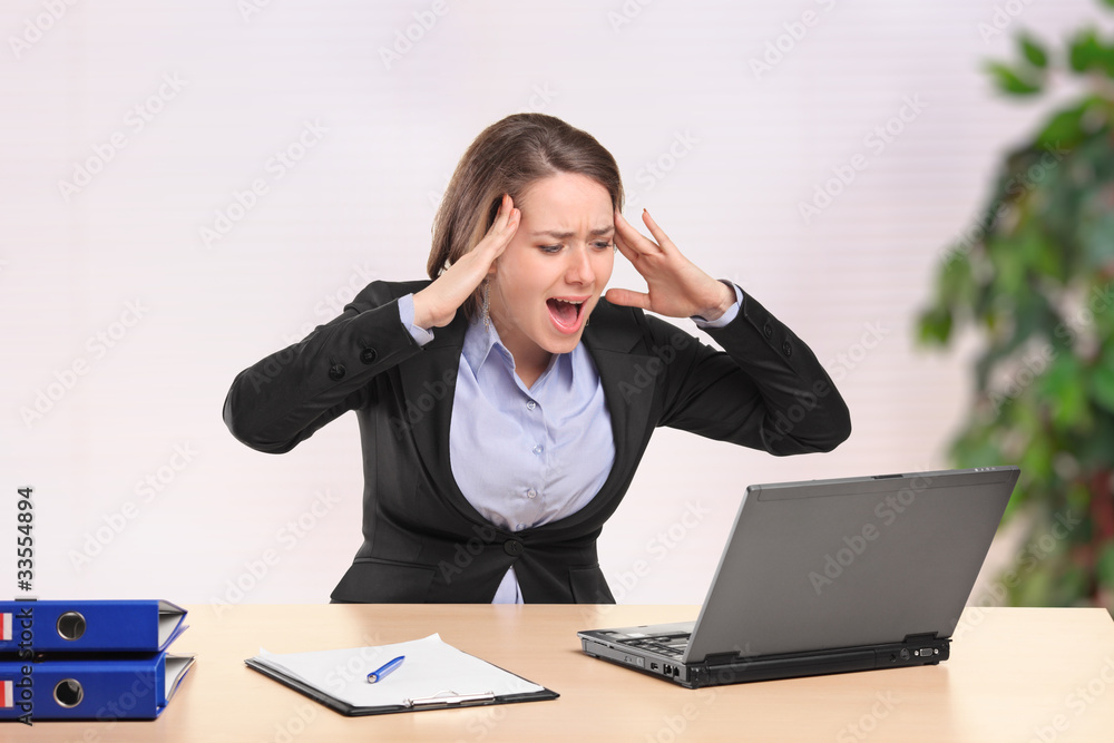Nervous young businesswoman yelling to a laptop in the office Nervous young businesswoman yelling to a laptop in the office