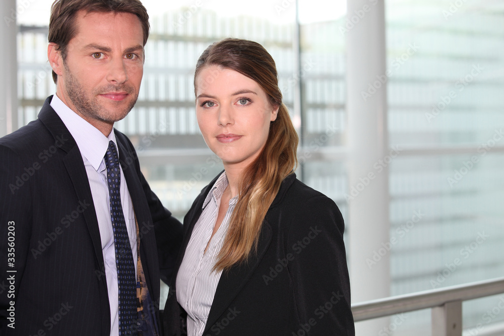 Business couple standing in front of a large window Business couple standing in front of a large window