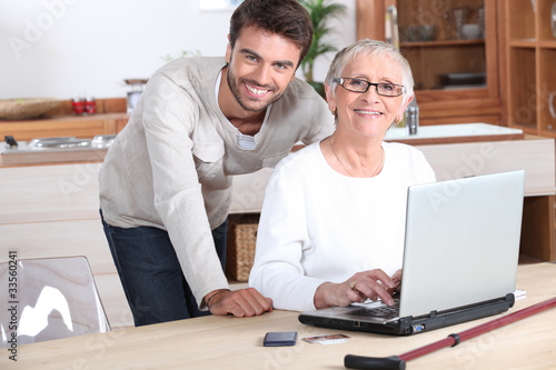 Принти на полотні Young man helping senior woman with a laptop compute