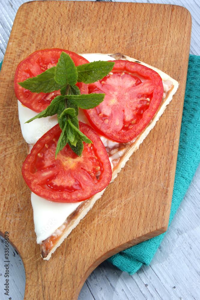 Pizza mit Mozzarella, Tomatenscheiben und Minze Pizza mit Mozzarella, Tomatenscheiben und Minze