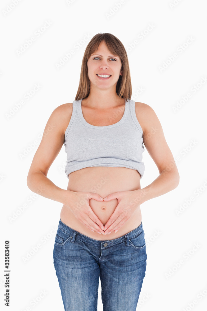 Lovely pregnant female posing while forming a heart with her han Lovely pregnant female posing while forming a heart with her han