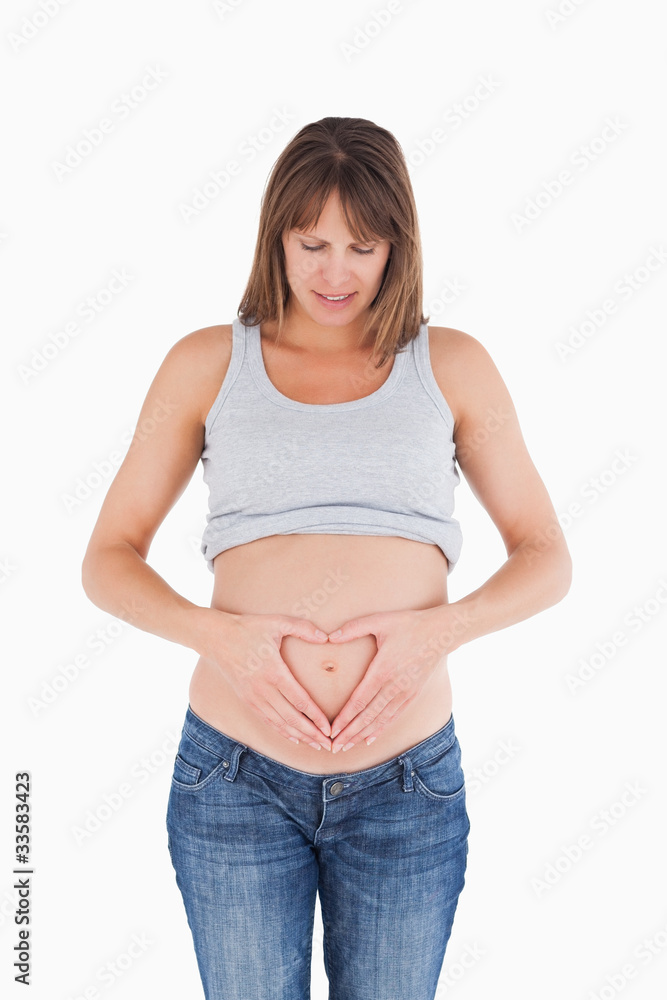 Attractive pregnant female posing while forming a heart with her Attractive pregnant female posing while forming a heart with her