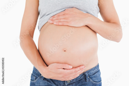 Close-up of a young pregnant woman caressing her belly while sta © WavebreakmediaMicro