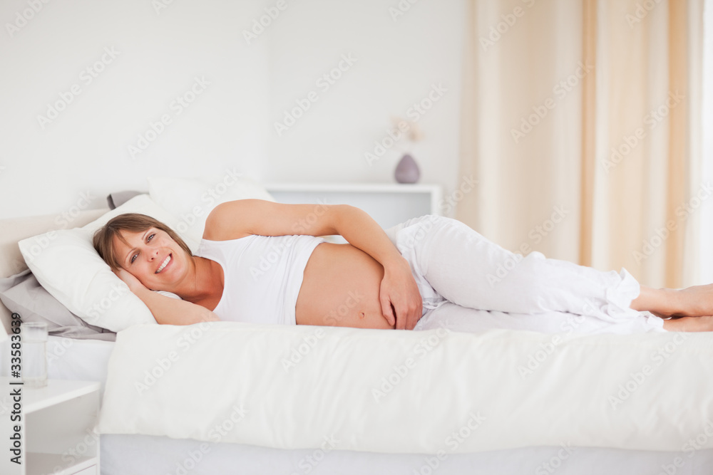 Attractive pregnant woman relaxing while lying on her bed Attractive pregnant woman relaxing while lying on her bed