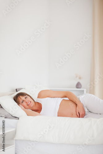 Good looking pregnant woman relaxing while lying on her bed