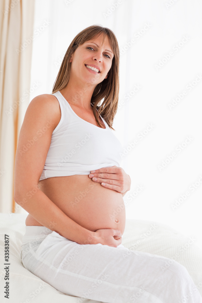 Portrait of a lovely pregnant female posing while sitting on a b Portrait of a lovely pregnant female posing while sitting on a b