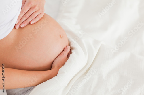 Close-up of a young pregnant female lying on a bed © WavebreakmediaMicro