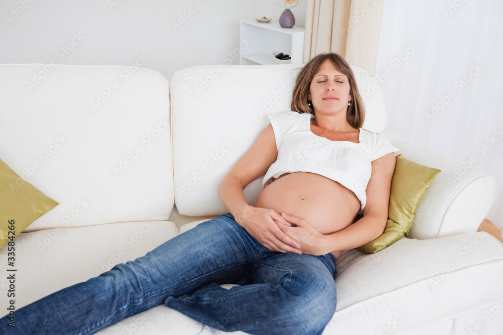 Beautiful pregnant woman posing while lying on a sofa Beautiful pregnant woman posing while lying on a sofa
