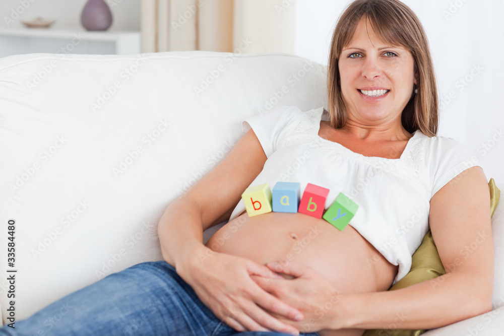Pretty pregnant woman playing with wooden blocks while lying on Pretty pregnant woman playing with wooden blocks while lying on