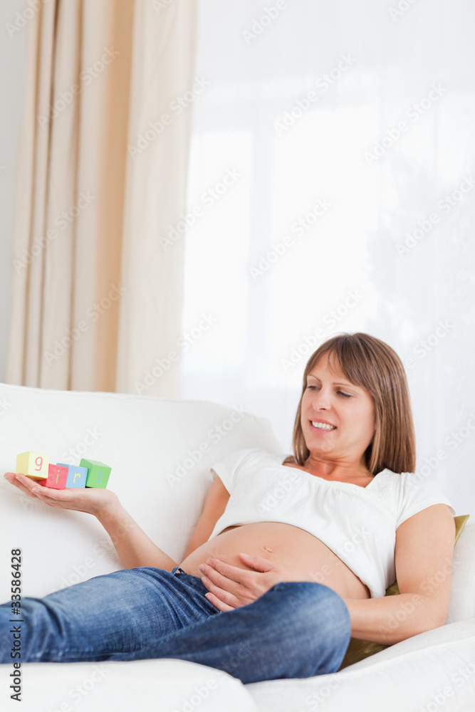 Attractive pregnant woman playing with wooden blocks and having Attractive pregnant woman playing with wooden blocks and having