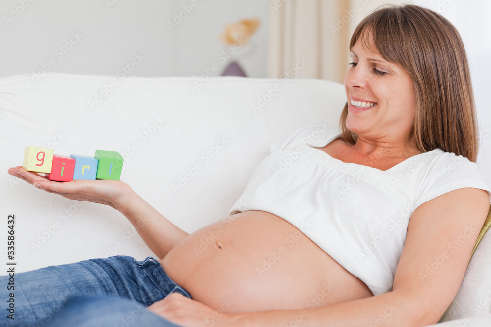 Beautiful pregnant woman playing with wooden blocks and having t Beautiful pregnant woman playing with wooden blocks and having t