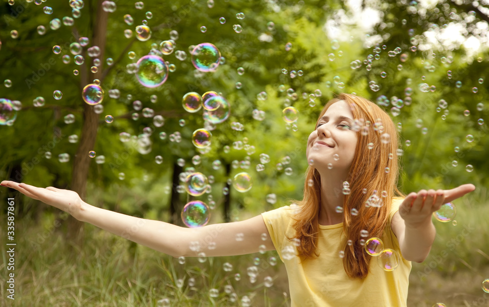 © Masson - Redhead girl in the park under soap bubble rain.