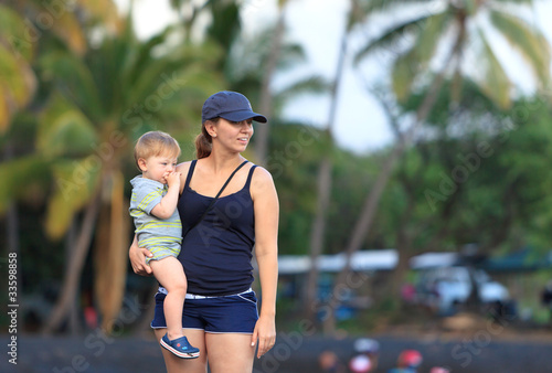 Young mother holding her son at a Hawaiian black sand beach