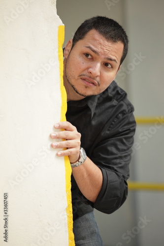 Man hiding behind a wall