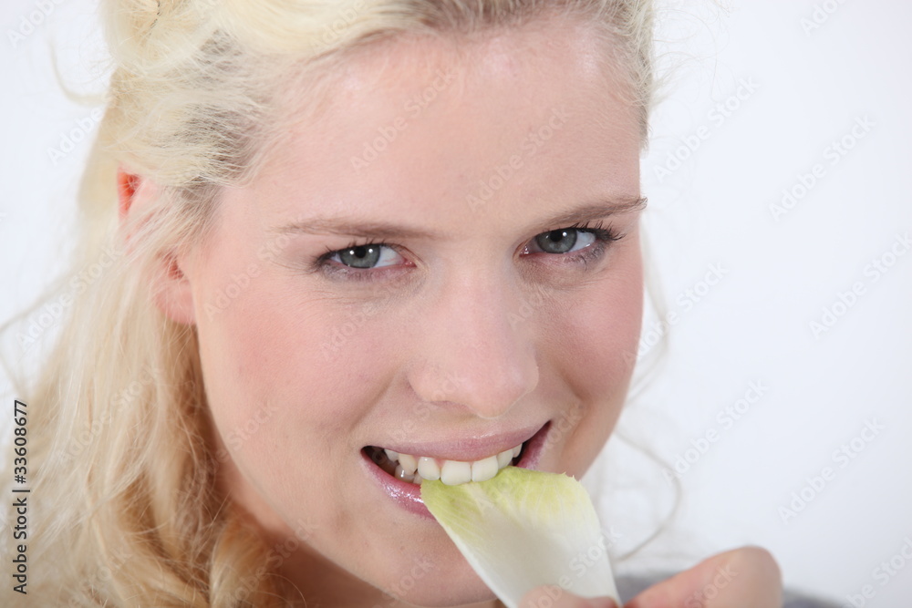 dynamic blonde woman crunching a leaf of endive dynamic blonde woman crunching a leaf of endive