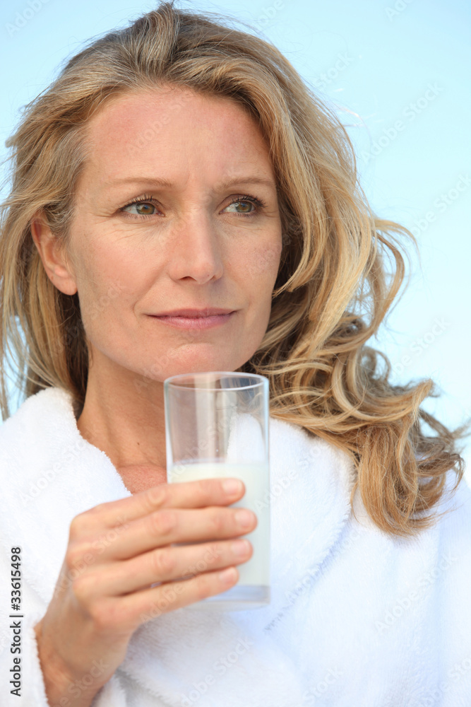 Woman outdoors in dressing gown holding glass of milk Woman outdoors in dressing gown holding glass of milk