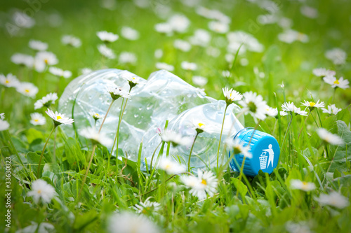 Plastic bottle on grass with recycle logo