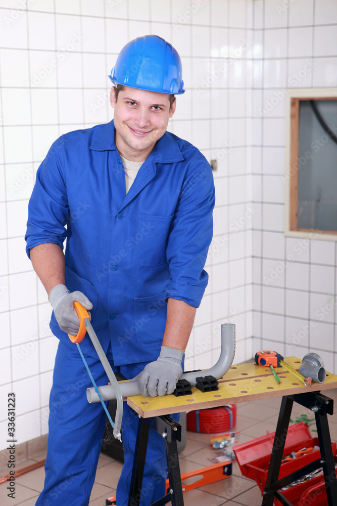 Young workman sawing plastic pipe Young workman sawing plastic pipe