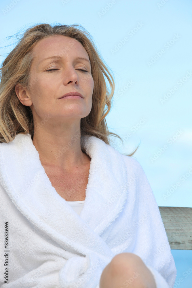 Woman in a bathrobe relaxing in the sunshine Woman in a bathrobe relaxing in the sunshine