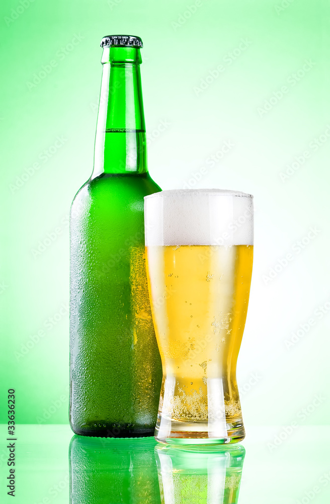 Chilled green bottle with condensate and a glass of beer lager o