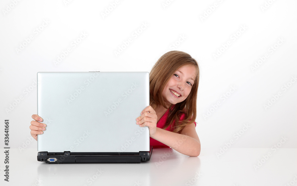 Portrait of blond little girl behind laptop computer Portrait of blond little girl behind laptop computer