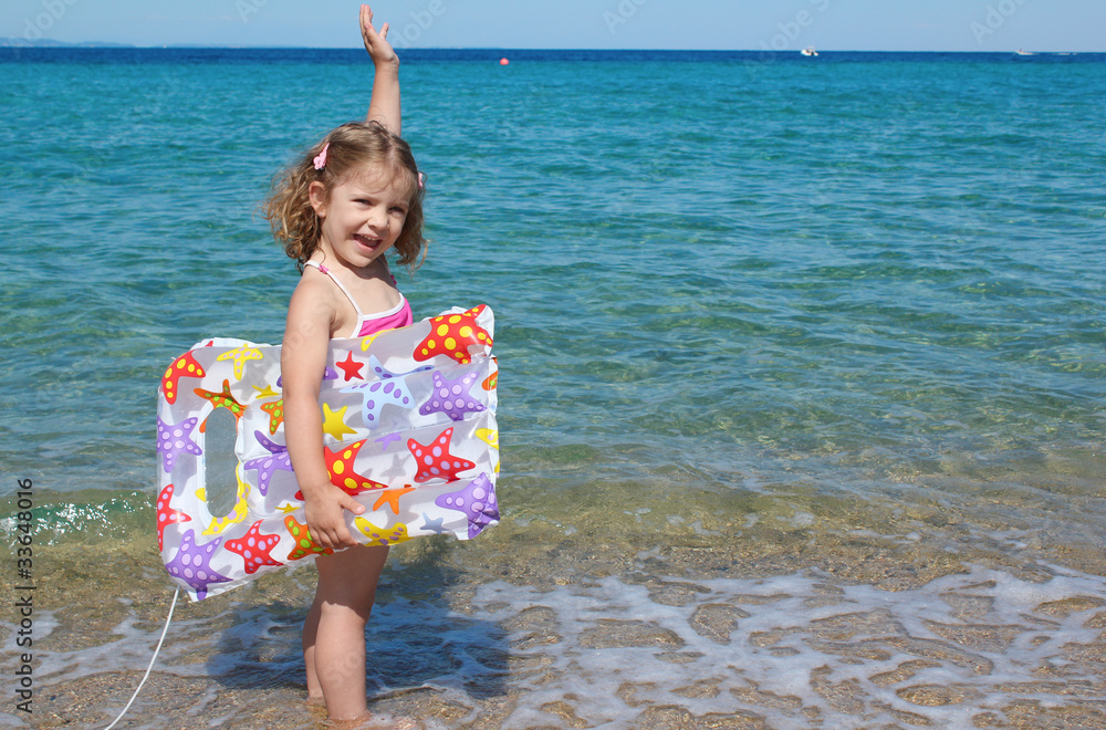 happy little girl standing in the sea with hand up Stock Photo | Adobe ...