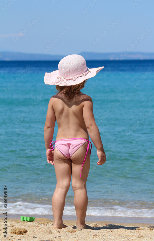 little girl with straw hat looking at sea little girl with straw hat looking at sea