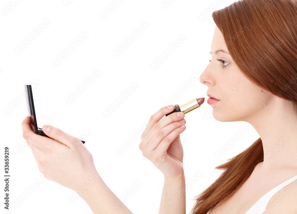 Fototapeta premium Ginger girl putting on lipstick