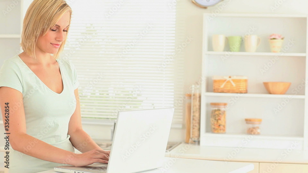 Charming woman drinking tea while using her laptop Charming woman drinking tea while using her laptop