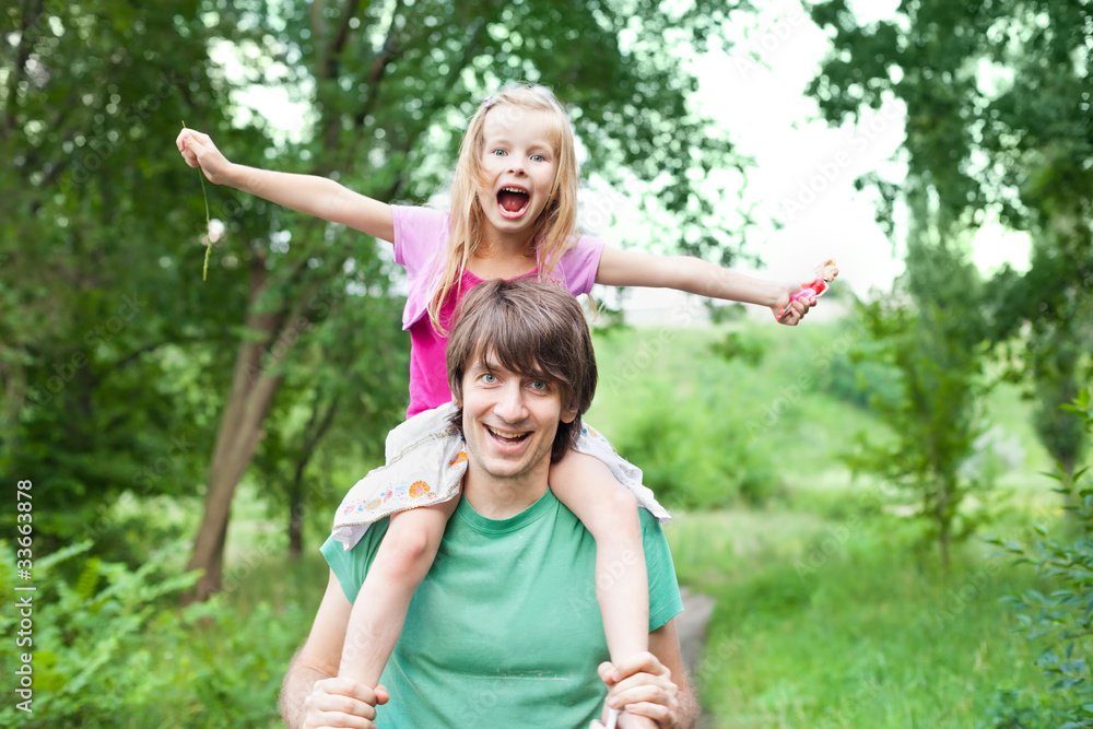 Fototapeta premium father and daughter.Young man holding blonde little girl on shou