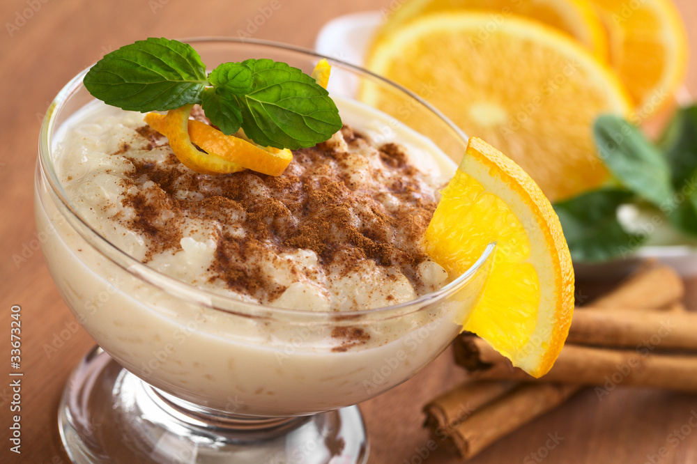 Rice pudding with cinnamon, orange slices and mint leaf