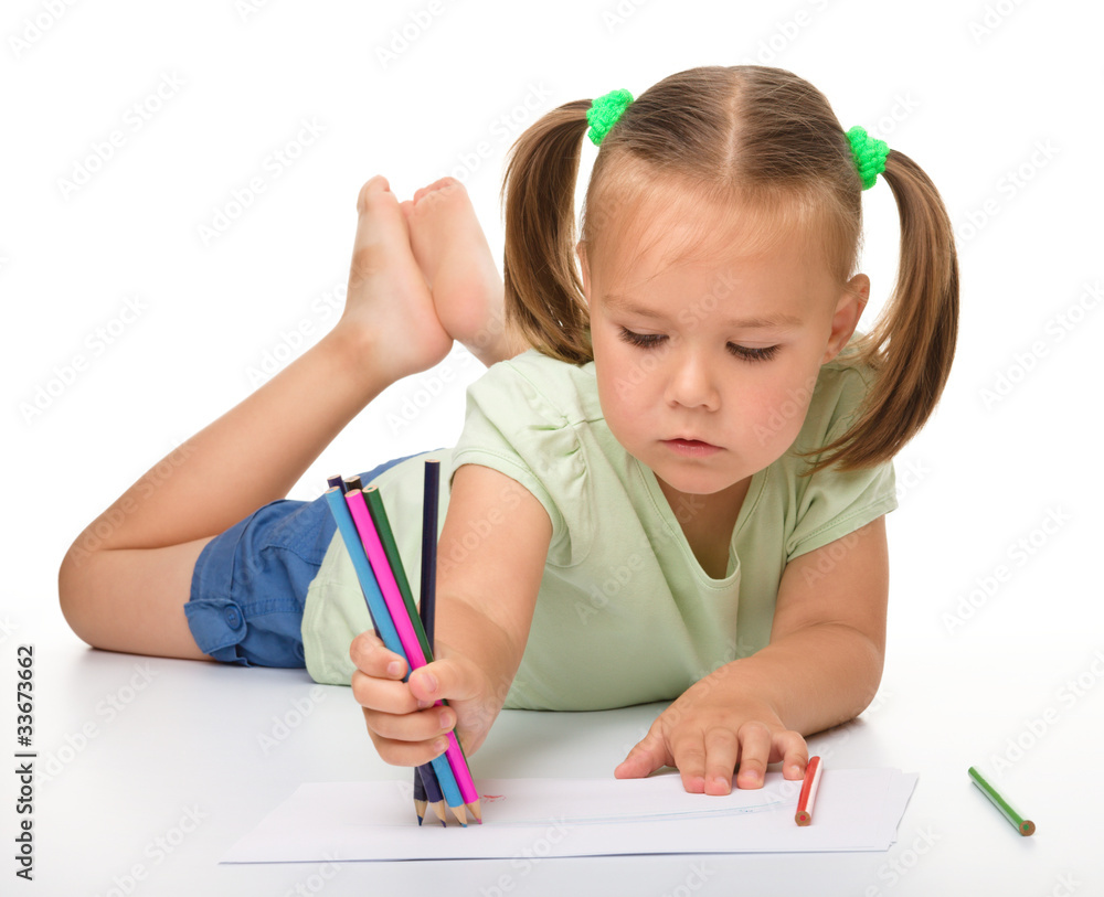 Little girl is drawing while laying on the floor