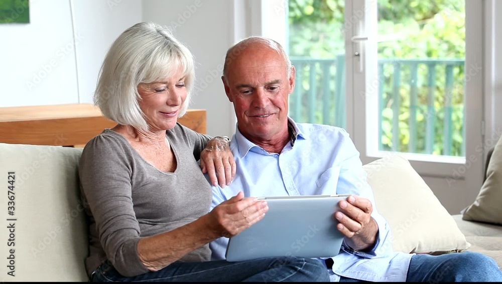 Senior couple using electronic tablet at home Senior couple using electronic tablet at home