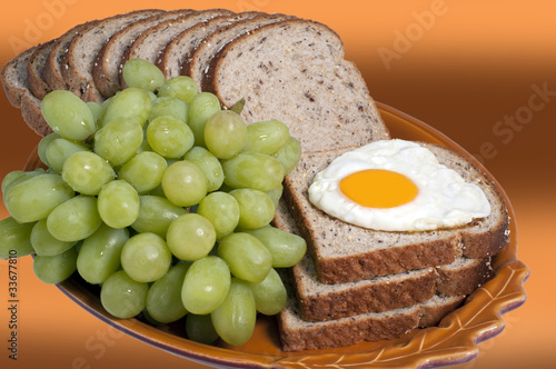 Plate with bread, egg and green grapes