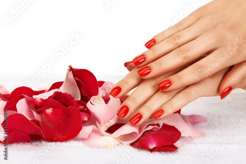 Closeup image of red manicure with leafs of rose