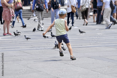 child playing with pigeons in the square