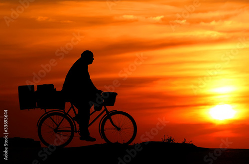Silhouette of bicyclist on orange sunset's background