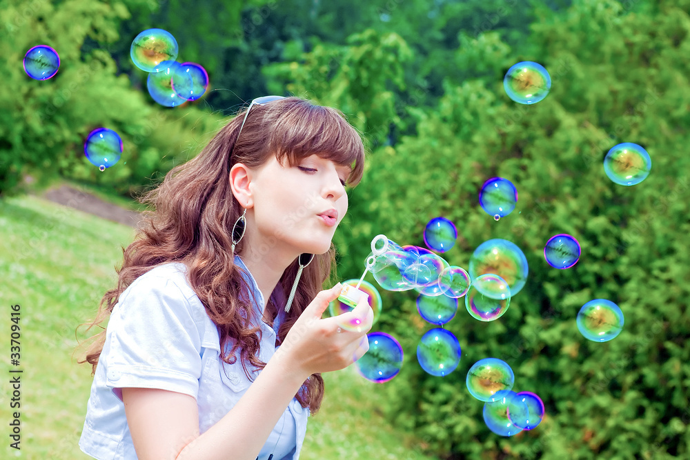 attractive girl inflating colorful soap bubbles in spring park attractive girl inflating colorful soap bubbles in spring park