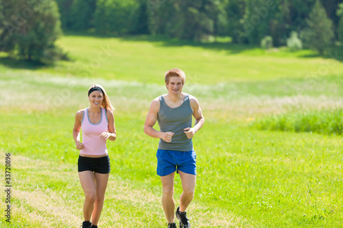 Fototapeta Naklejka Na Ścianę i Meble -  Sportive young couple jogging meadows sunny summer