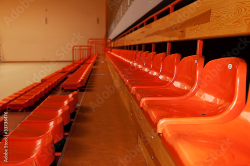 Orange, plastic seats in rows at sport indoor arena. © Bart