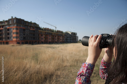 Woman watching with binoculars building construction