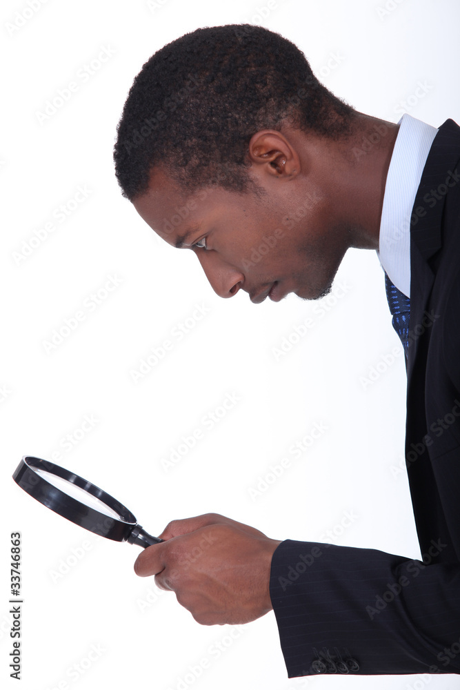 black man looking through a magnifying glass black man looking through a magnifying glass