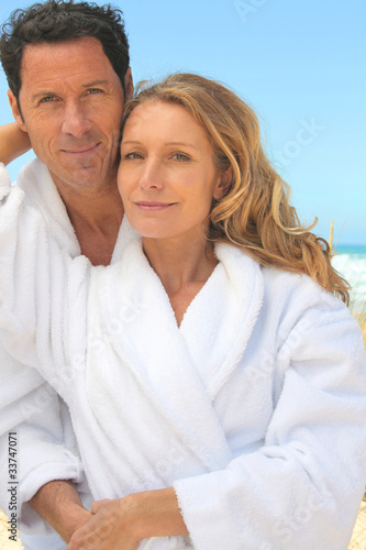 Man and woman in toweling robes on the beach © auremar